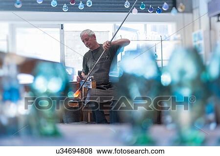 Stock Photo - Glassblower with large blob of hot glass. Fotosearch
