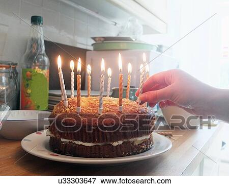 Hand of young woman placing lit candles on birthday cake View Large Photo Image Stock Photo - Hand of young woman placing lit candles on birthday cake. Fotosearch