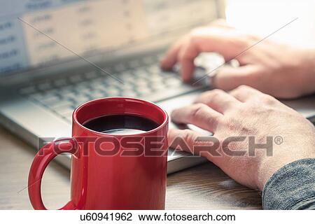 Stock Image - Hands of man typing on laptop at desk. Fotosearch