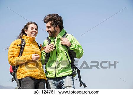 Stock Image - Hiking couple against blue sky laughing. Fotosearch