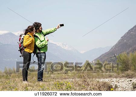 Stock Image - Hiking couple taking smartphone selfie, Vogogna, Verbania, Piemonte, Italy. Fotosearch