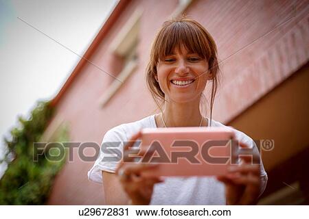 Low and view of mid adult woman using smartphone, smiling View Large Photo Image Stock Image - Low and view of mid adult woman using smartphone, smiling. Fotosearch