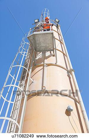 Stock Photo - Low angle portrait of worker on smoke stack viewing platform. Fotosearch