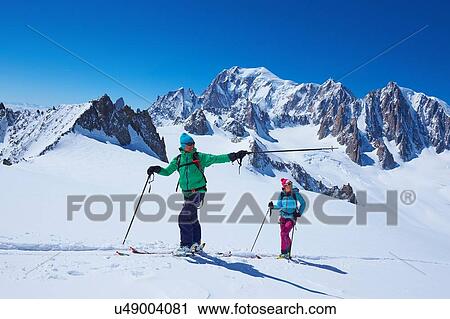 Stock Image - Male and female skiers pointing from Mont Blanc massif, Graian Alps, France. Fotosearch