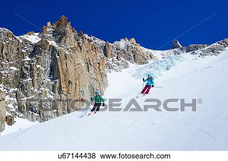 Stock Photo - Male and female skiers skiing down Mont Blanc massif, Graian Alps, France. Fotosearch