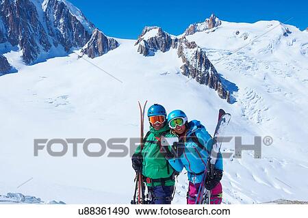 Stock Image - Male and female skiers taking smartphone selfie on Mont Blanc massif, Graian Alps, France. Fotosearch