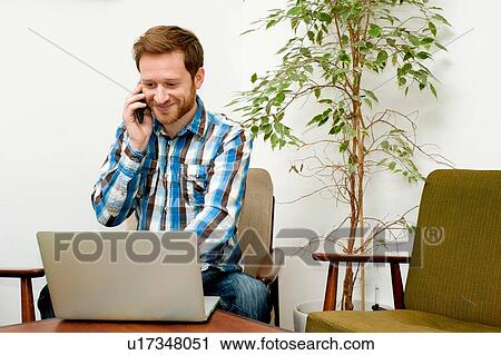 Stock Image - Male customer using laptop and smartphone in cafe. Fotosearch