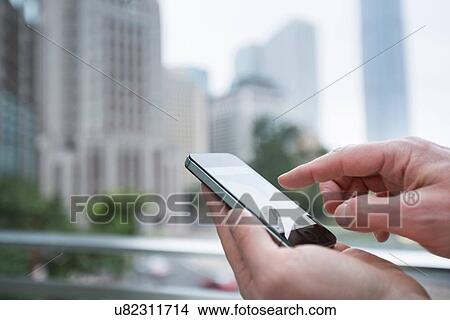 Picture - Man using smartphone outdoors, focus on hands, Hong Kong, China. Fotosearch