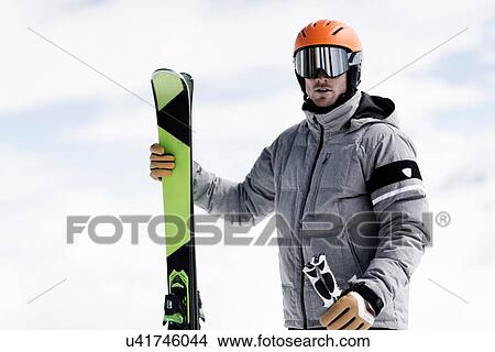 Man wearing helmet and ski goggles holding skis, portrait View Large Photo Image Picture - Man wearing helmet and ski goggles holding skis, portrait. Fotosearch