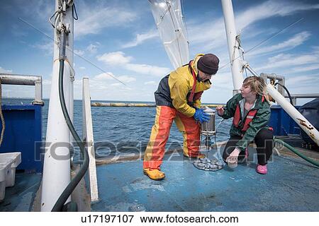 Stock Photo - Marine biologists taking samples from plankton net on research ship. Fotosearch