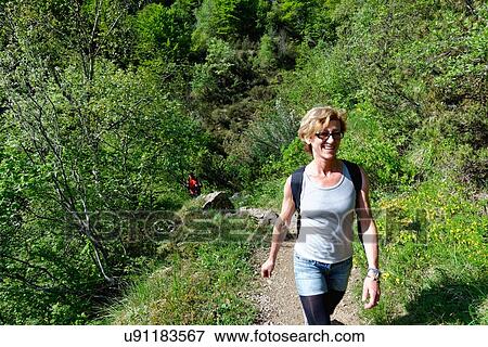 Mature female hiker hiking up hillside path View Large Photo Image Stock Photo - Mature female hiker hiking up hillside path. Fotosearch