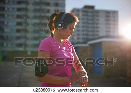 Mature female runner checking wrist watch at dusk View Large Photo Image Stock Photography - Mature female runner checking wrist watch at dusk. Fotosearch
