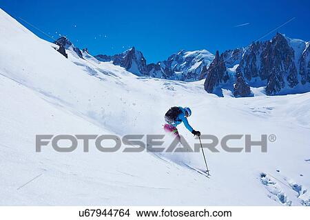 Picture - Mature female skier moving down Mont Blanc massif, Graian Alps, France. Fotosearch