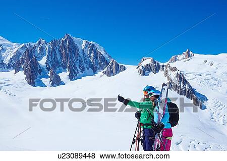 Stock Photo - Mature male and female skiers taking smartphone selfie on Mont Blanc massif, Graian Alps, France. Fotosearch