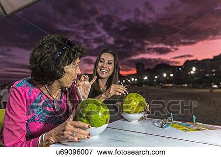 Mature woman and mother drinking from coconut shells at beach at night, Copacabana, Rio de Janeiro, Brazil View Large Photo Image Stock Photo - Mature woman and mother drinking from coconut shells at beach at night, Copacabana, Rio de Janeiro, Brazil. Fotosearch