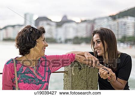Stock Photo - Mature woman holding hand of her mother at beach, Copacabana, Rio de Janeiro, Brazil. Fotosearch