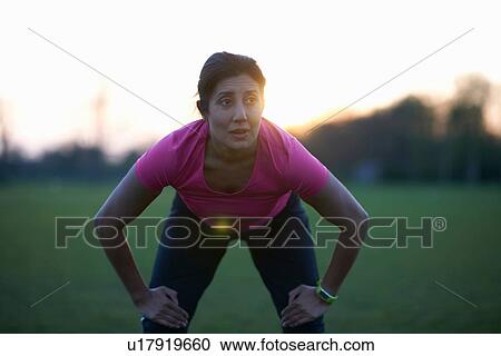 Stock Image - Mature woman taking a break from exercise in park. Fotosearch