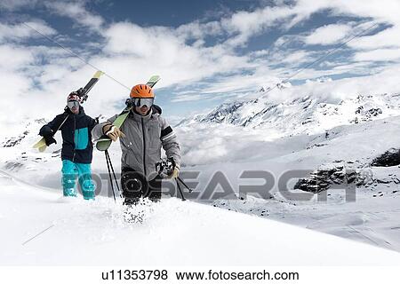 Stock Photo - Men carrying skis in snow, Zermatt, Valais, Switzerland. Fotosearch