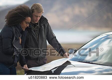 Stock Image - Mid adult couple by car with map. Fotosearch