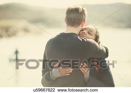 Stock Image - Mid adult couple hugging in sunlight. Fotosearch