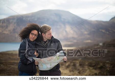 Picture - Mid adult couple in mountains with map. Fotosearch