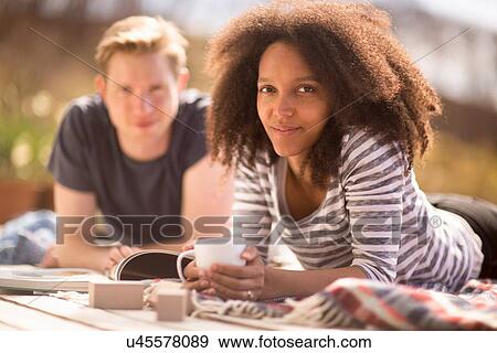 Stock Photo - Mid adult couple relaxing outdoors, woman looking at camera. Fotosearch