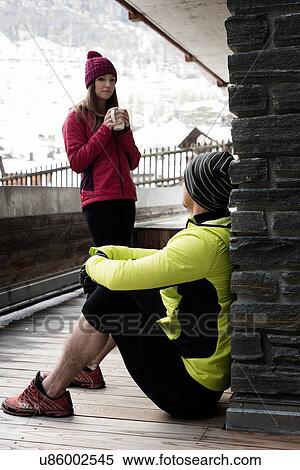 Stock Photography - Mid adult couple wearing winter clothes, woman holding coffee. Fotosearch