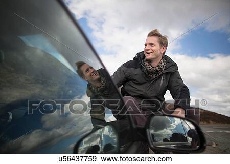 Mid adult man by car looking away, smiling View Large Photo Image Stock Photo - Mid adult man by car looking away, smiling. Fotosearch