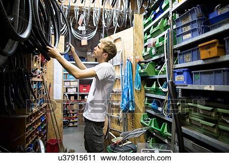 Mid adult man in repair shop choosing bicycle tyre View Large Photo Image Stock Image - Mid adult man in repair shop choosing bicycle tyre. Fotosearch