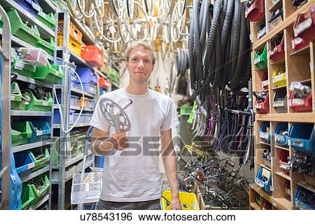 Mid adult man in storage room holding bicycle part View Large Photo Image Stock Photograph - Mid adult man in storage room holding bicycle part. Fotosearch