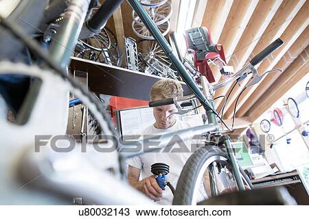 Mid adult man in workshop inflating bicycle tyre, view through frame View Large Photo Image Stock Image - Mid adult man in workshop inflating bicycle tyre, view through frame. Fotosearch