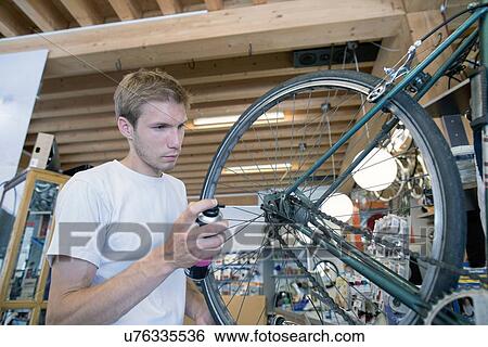 Mid adult man in workshop lubricating bicycle wheel View Large Photo Image Stock Photograph - Mid adult man in workshop lubricating bicycle wheel. Fotosearch