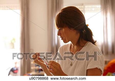 Mid adult woman at home using nail file View Large Photo Image Stock Photo - Mid adult woman at home using nail file. Fotosearch