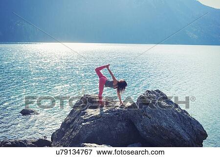 Mid adult woman, balancing on rock beside lake, in yoga position View Large Photo Image Stock Photo - Mid adult woman, balancing on rock beside lake, in yoga position. Fotosearch