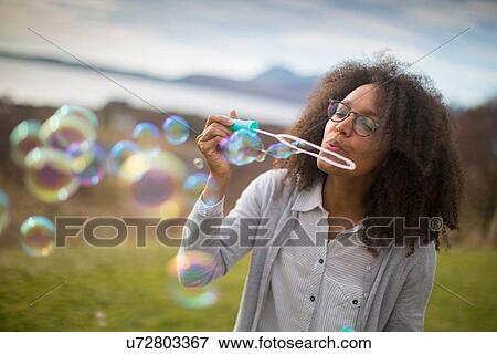 Mid adult woman blowing bubbles View Large Photo Image Stock Photo - Mid adult woman blowing bubbles. Fotosearch