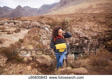 Stock Image - Mid adult woman hiking, Fairy Pools, Isle of Skye, Hebrides, Scotland. Fotosearch