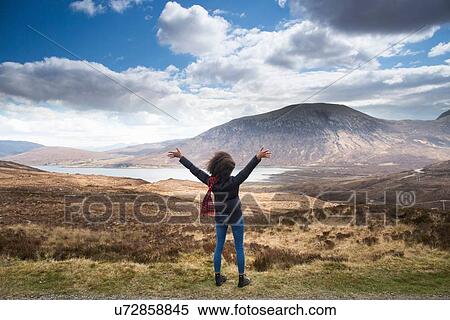 Stock Photography - Mid adult woman in mountains with arms up, Isle of Skye, Hebrides, Scotland. Fotosearch