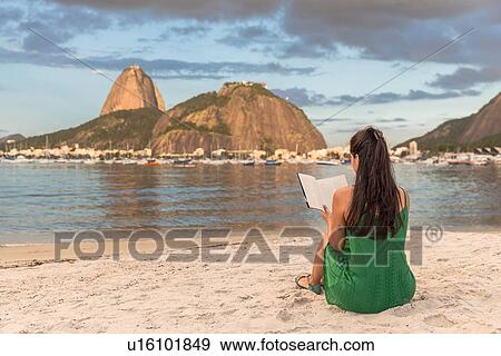 Mid adult woman sitting in beach, reading book, Sugarloaf mountain in background, Botafogo bay, Rio de Janeiro, Brazil View Large Photo Image Stock Photo - Mid adult woman sitting in beach, reading book, Sugarloaf mountain in background, Botafogo bay, Rio de Janeiro, Brazil. Fotosearch