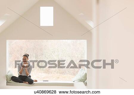 Mid adult woman sitting in window seat View Large Photo Image Stock Photo - Mid adult woman sitting in window seat. Fotosearch