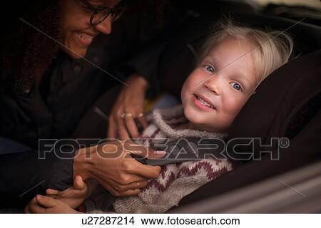 Picture - Mother adjusting son's seatbelt in car. Fotosearch