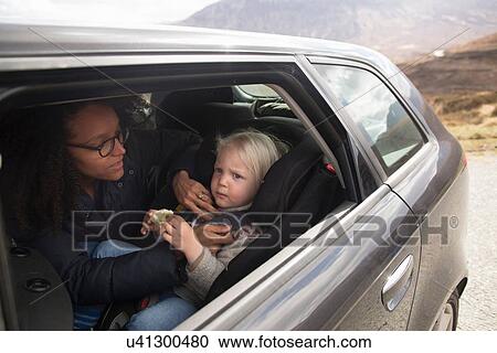 Stock Image - Mother adjusting son's seatbelt in car. Fotosearch