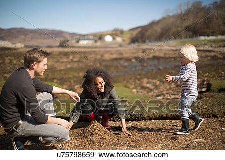 Mother and father playing with son, making pile of soil View Large Photo Image Stock Photo - Mother and father playing with son, making pile of soil. Fotosearch