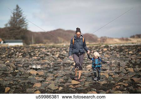 Mother and son holding hands walking on rocks View Large Photo Image Stock Image - Mother and son holding hands walking on rocks. Fotosearch