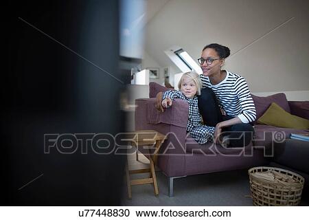 Stock Image - Mother and son sitting on sofa watching television. Fotosearch