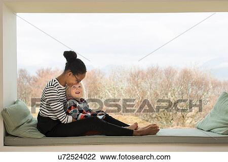 Mother and son sitting on window seat View Large Photo Image Stock Image - Mother and son sitting on window seat. Fotosearch