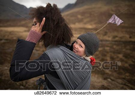 Stock Image - Mother carrying son in sling. Fotosearch