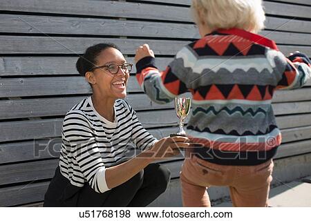 Stock Photo - Mother giving son trophy. Fotosearch