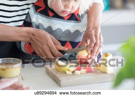 Mother helping son chop apple View Large Photo Image Picture - Mother helping son chop apple. Fotosearch