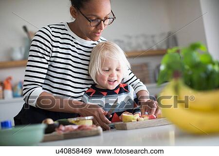 Stock Photo - Mother helping sone prepare food in kitchen. Fotosearch