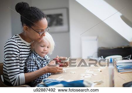 Stock Image - Mother showing son how to use scissors. Fotosearch